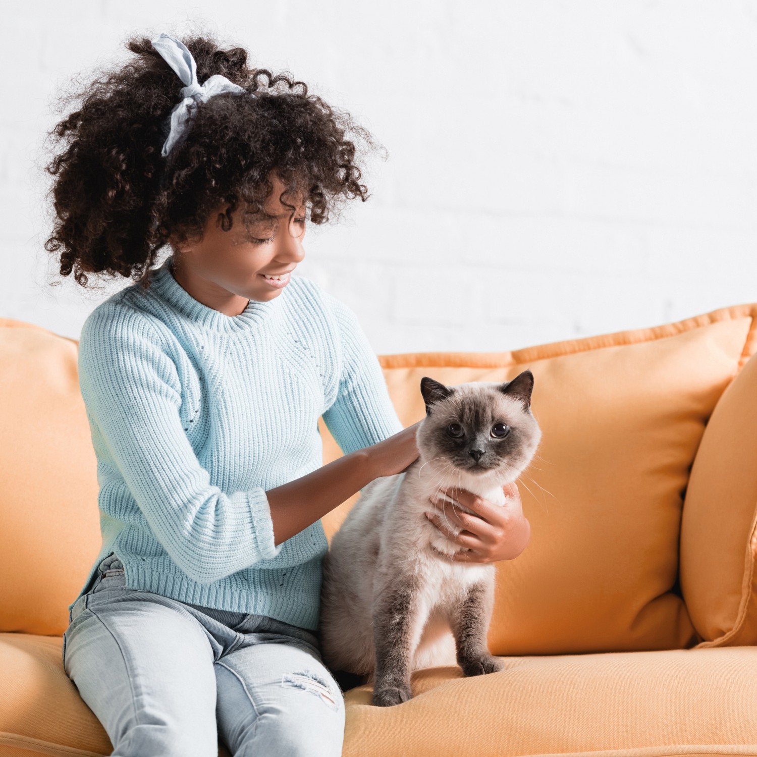 Girl on couch petting cat